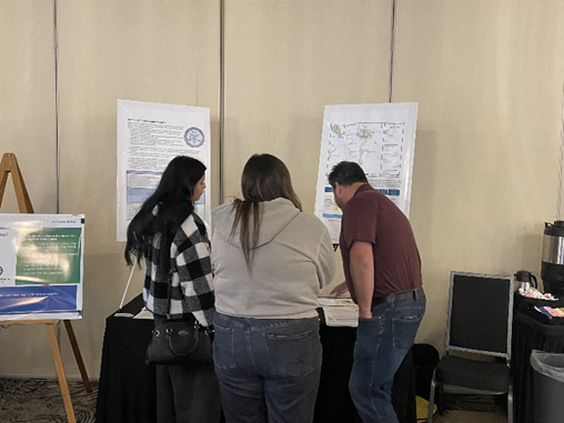 Photo of people standing at a table with poster boards in the background.