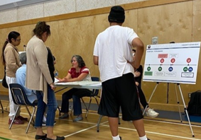 Photo of three individuals talking and looking at a poster.